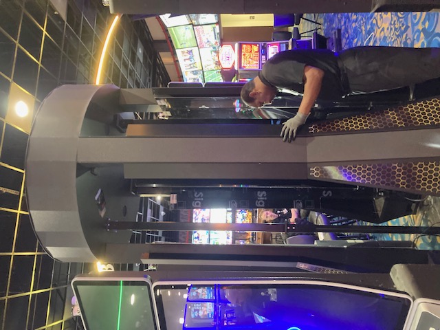 Technician fitting panels on a tall circular casino-floor sign enclosure.